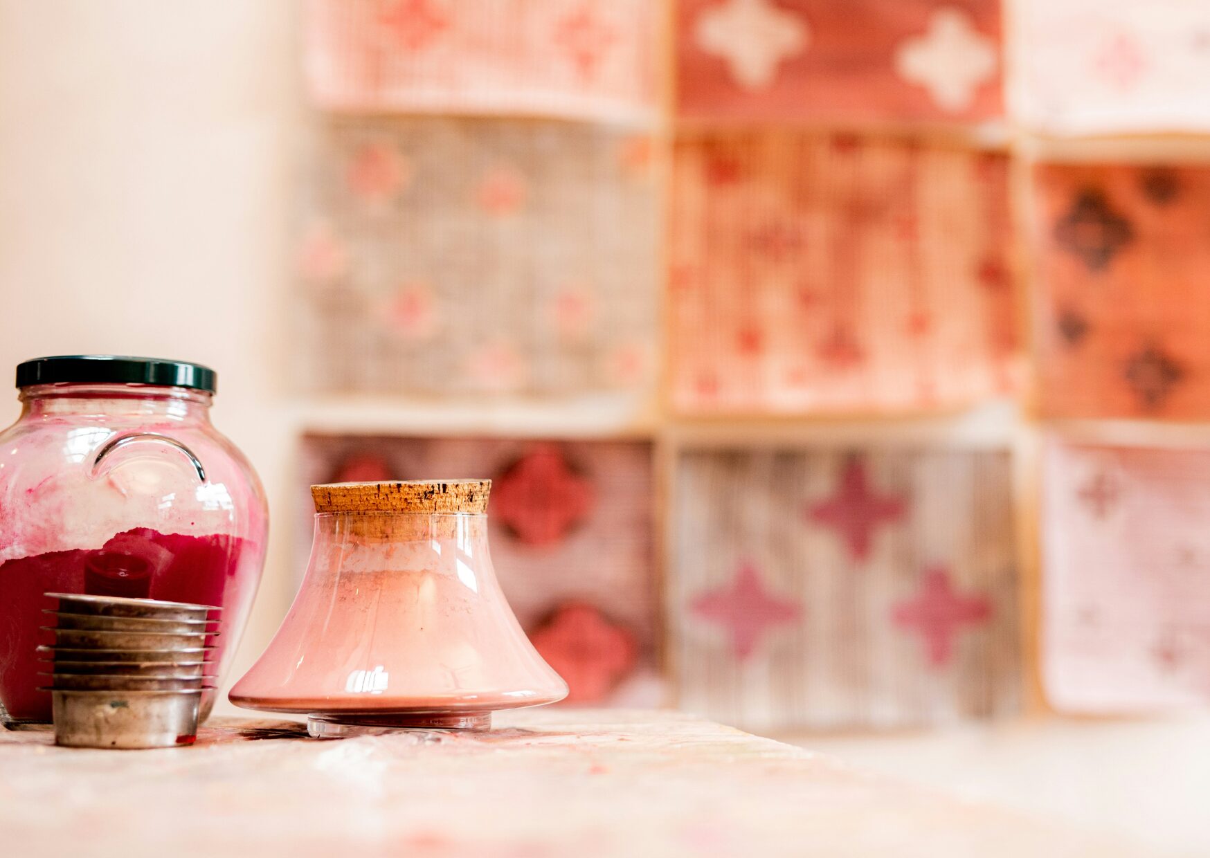 Farbpigmente in verschiedenen Rosetönen ind verkorkten Glasbehältern. An der Wand hängen Kunstwerke. Warum ist Kreativität wichtig?