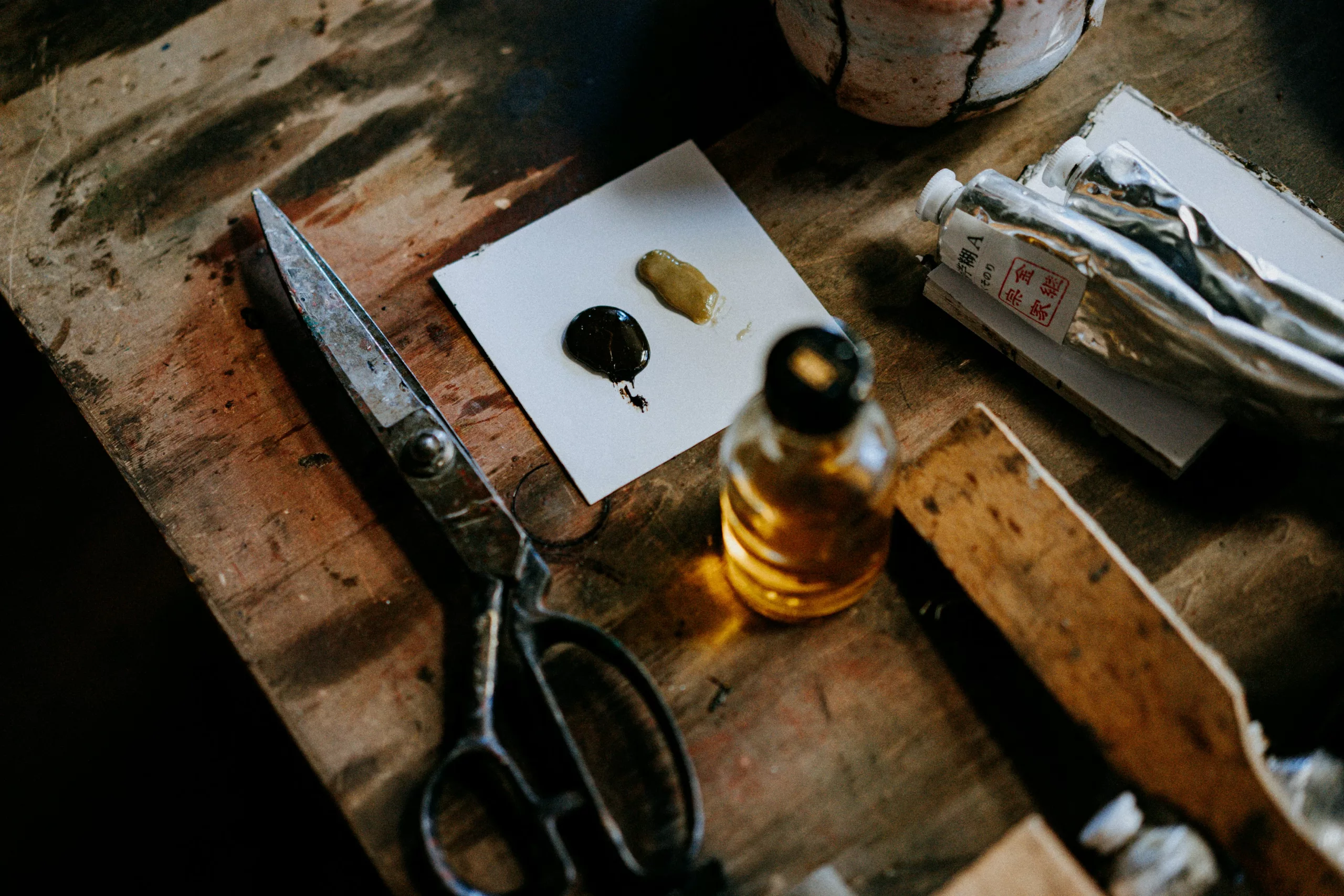 Auf einem Holztisch liegen verschiedene Materialien eines Künstlers. Scheitern ist ein Teil des kreativen Prozesses. An artist's various materials lie on a wooden table. Failure is part of the creative process.