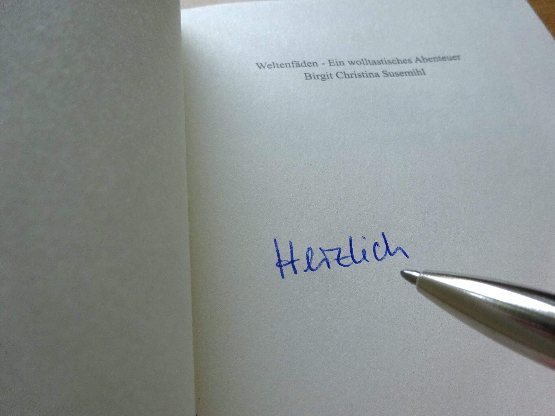 Erste Seite des Buches Weltenfäden. Die Autorin hat begonnen zu signieren.
